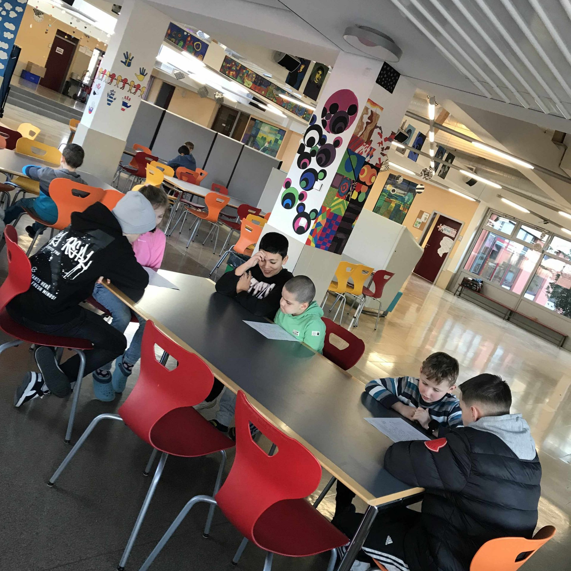 Mehrere Lesepaare – Erstklässler lesen – Siebtklässler hören zu – Mensa