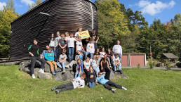 Gruppenfoto der Klassensprecherinnen und Klassensprecher der Klassen 3 bis 9 der Grund- und Mittelschule Bad Rodach bei den SMV-Planungstagen in Neukirchen vor dem Holzgebäude der Jugendbildungsstätte.