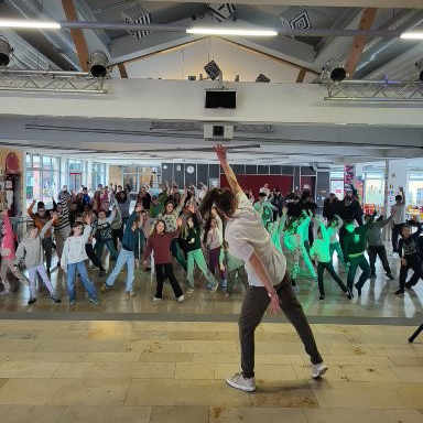 Gro&szlig;e Sch&uuml;lergruppe tanzt gemeinsam in der Aula zum neuen Schultanz.