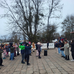 Schülerinnen und Schüler tanzen gemeinsam draußen auf dem Pausenhof.